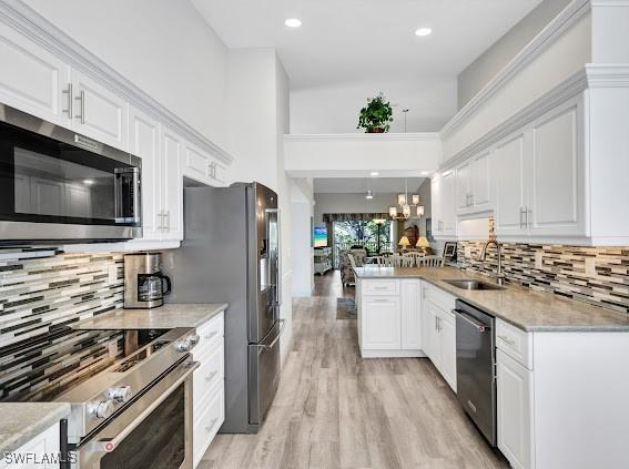 kitchen with hanging light fixtures, white cabinetry, appliances with stainless steel finishes, and sink