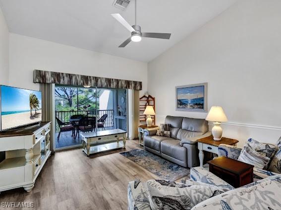 living room with hardwood / wood-style floors, vaulted ceiling, and ceiling fan