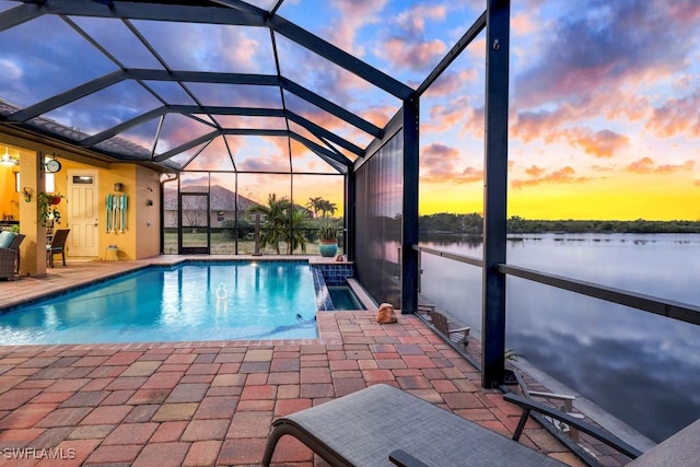 pool at dusk featuring a water view, glass enclosure, and a patio area