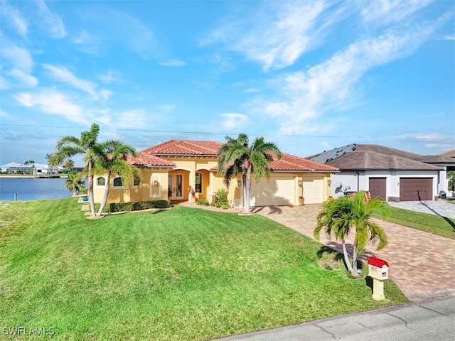 mediterranean / spanish house featuring a water view, a garage, and a front yard