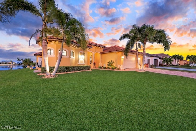 mediterranean / spanish house with a garage, a lawn, and a water view