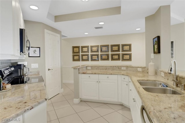 kitchen with sink, white cabinets, light tile patterned floors, light stone counters, and kitchen peninsula
