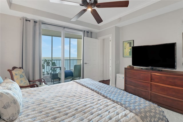 bedroom with access to exterior, a tray ceiling, ornamental molding, and ceiling fan
