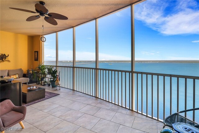 sunroom featuring ceiling fan and a water view