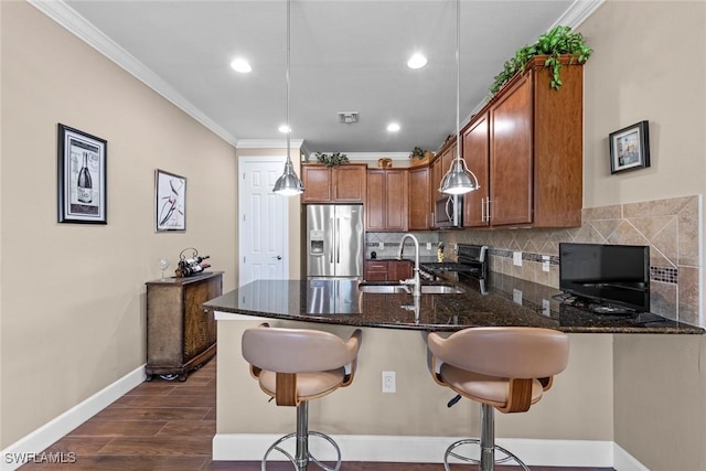 10641 Jackson Square Dr, Estero, FL 33928 - kitchen with brown cabinetry, a peninsula, stainless steel appliances, a sink, and backsplash