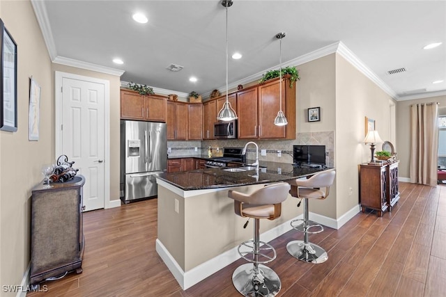 10641 Jackson Square Dr, Estero, FL 33928 - kitchen featuring a peninsula, appliances with stainless steel finishes, brown cabinetry, and wood finished floors