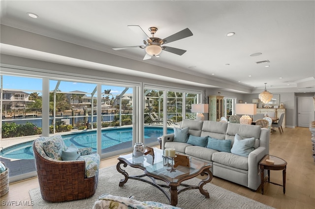 living area featuring ornamental molding, light wood-type flooring, visible vents, and a healthy amount of sunlight