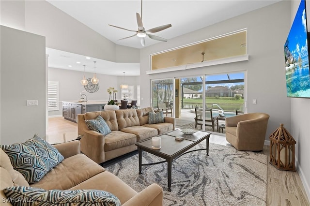 living room featuring ceiling fan, high vaulted ceiling, and light wood-type flooring