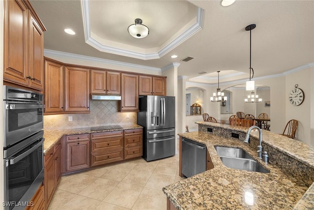 kitchen featuring appliances with stainless steel finishes, sink, light stone counters, and a tray ceiling