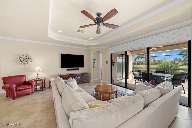 tiled living room with ornamental molding, a raised ceiling, and ceiling fan