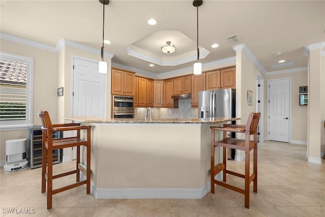 kitchen with decorative light fixtures, a kitchen breakfast bar, light stone counters, stainless steel appliances, and a center island with sink