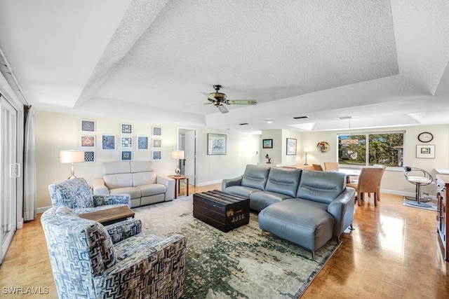 living room featuring a raised ceiling, ceiling fan, and a textured ceiling