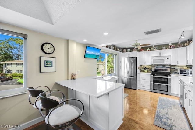 kitchen featuring white cabinetry, stainless steel appliances, a kitchen breakfast bar, and kitchen peninsula