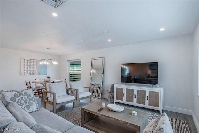 living area featuring baseboards, visible vents, a chandelier, and wood finished floors