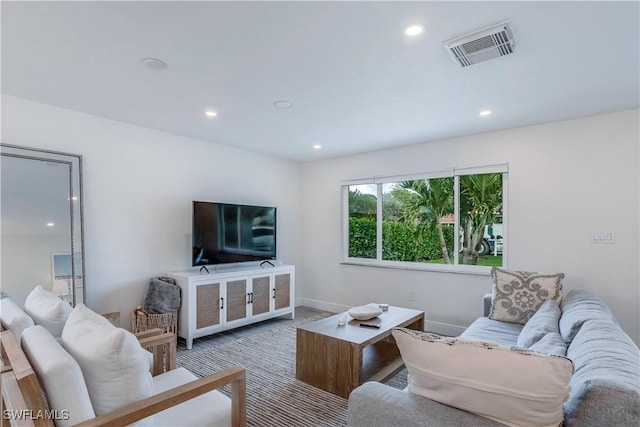 carpeted living area featuring baseboards, visible vents, and recessed lighting