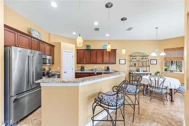 kitchen featuring hanging light fixtures, light stone countertops, visible vents, and appliances with stainless steel finishes