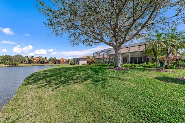 view of yard featuring glass enclosure, a water view, and ceiling fan