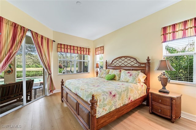 bedroom featuring access to outside, multiple windows, and wood finished floors