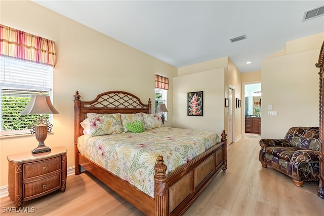 bedroom with visible vents, wood finished floors, and ensuite bathroom