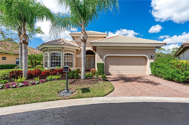 mediterranean / spanish house with decorative driveway, french doors, stucco siding, a garage, and a tiled roof