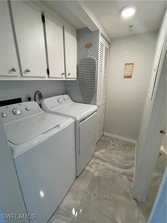 laundry room featuring baseboards, cabinet space, marble finish floor, and washing machine and dryer