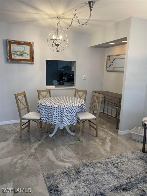 dining room featuring a notable chandelier, marble finish floor, and baseboards