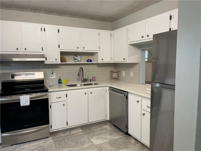 kitchen with an ornate ceiling, a sink, under cabinet range hood, appliances with stainless steel finishes, and tasteful backsplash