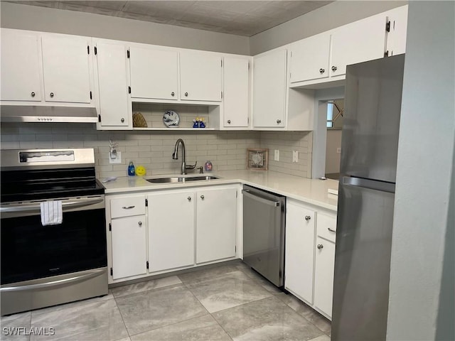 kitchen featuring under cabinet range hood, light countertops, decorative backsplash, appliances with stainless steel finishes, and a sink