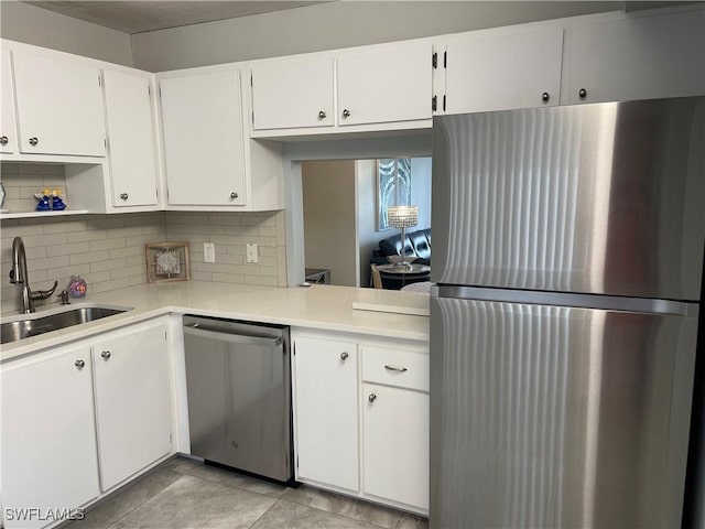 kitchen with light countertops, decorative backsplash, white cabinets, stainless steel appliances, and a sink