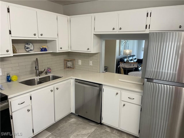 kitchen featuring light countertops, decorative backsplash, white cabinets, stainless steel appliances, and a sink