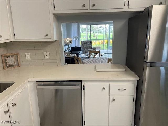 kitchen with decorative backsplash, white cabinetry, appliances with stainless steel finishes, and light countertops