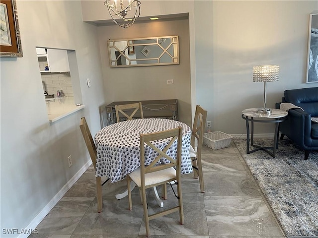 dining area with a notable chandelier, marble finish floor, and baseboards