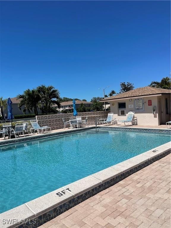 community pool with a patio and fence