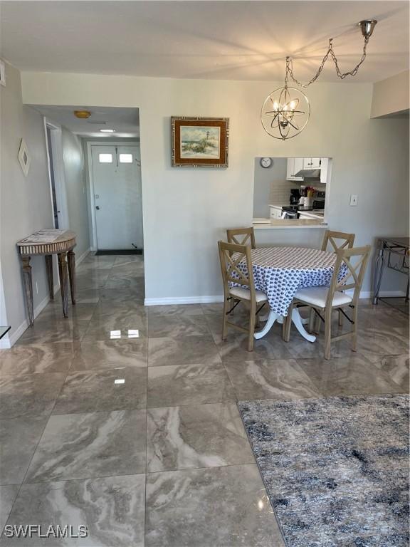 dining space with a notable chandelier, baseboards, and marble finish floor