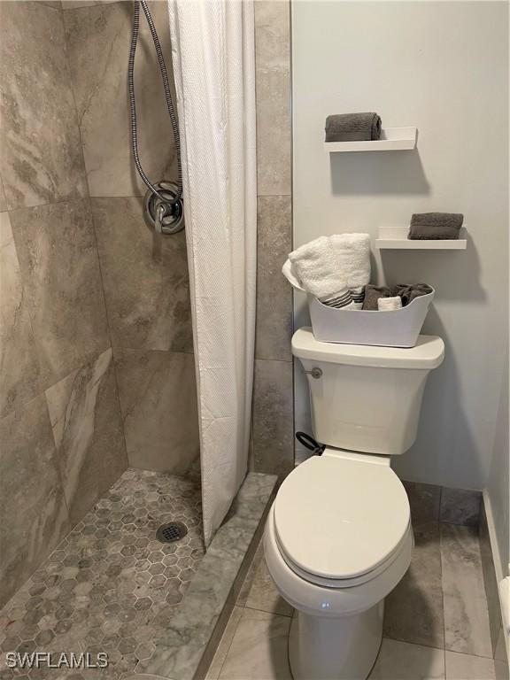 bathroom with tile patterned flooring, a shower stall, and toilet