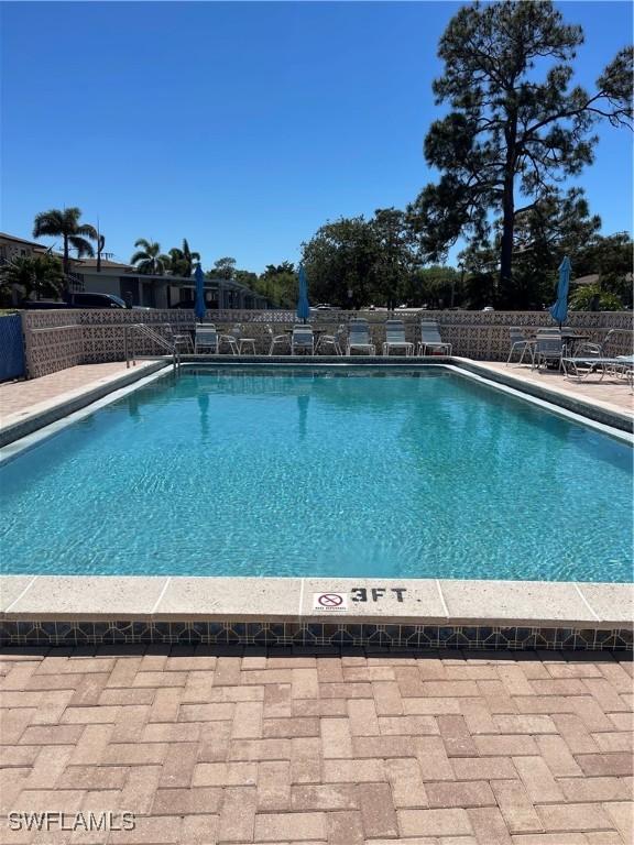 community pool with a patio and fence