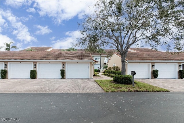 townhome / multi-family property featuring community garages, stucco siding, and a tiled roof