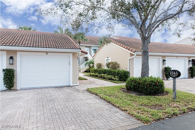 view of front of home with a tile roof, a garage, and stucco siding