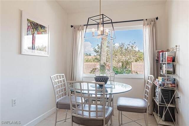 dining area with baseboards, a notable chandelier, and light tile patterned flooring