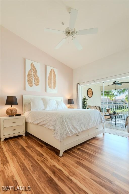 bedroom featuring access to exterior, a ceiling fan, light wood-type flooring, and vaulted ceiling