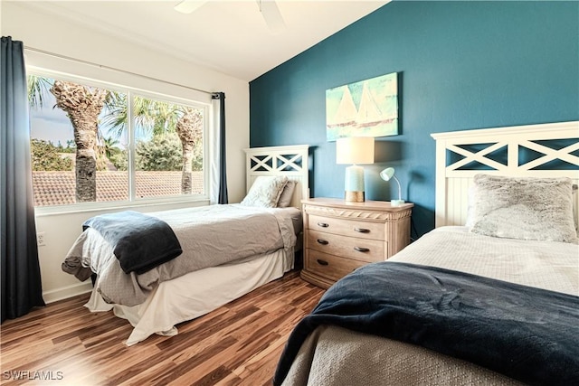 bedroom featuring baseboards, wood finished floors, a ceiling fan, and vaulted ceiling