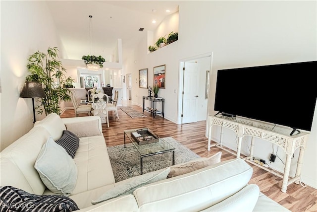 living area with recessed lighting, baseboards, a towering ceiling, and wood finished floors