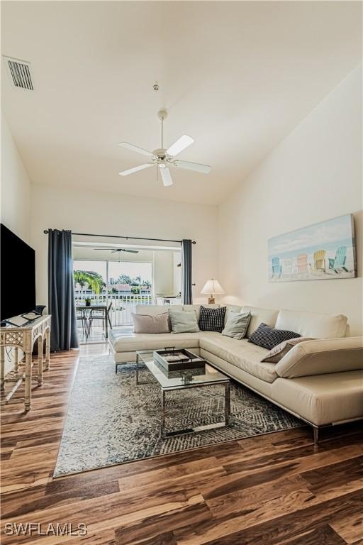 living room with visible vents, lofted ceiling, wood finished floors, and a ceiling fan