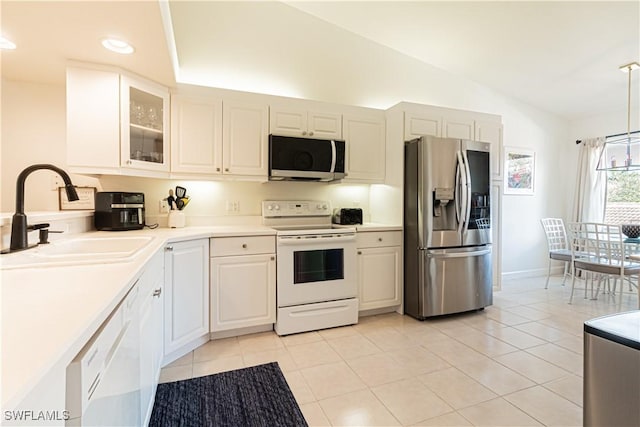 kitchen with a sink, vaulted ceiling, light countertops, glass insert cabinets, and appliances with stainless steel finishes