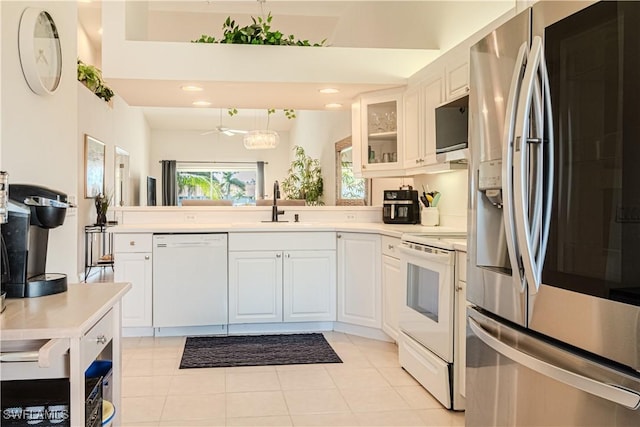 kitchen featuring white appliances, a sink, light countertops, glass insert cabinets, and white cabinetry