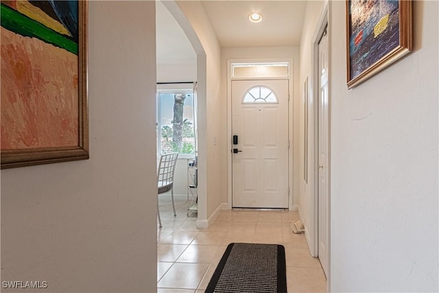 doorway featuring light tile patterned floors, baseboards, and arched walkways