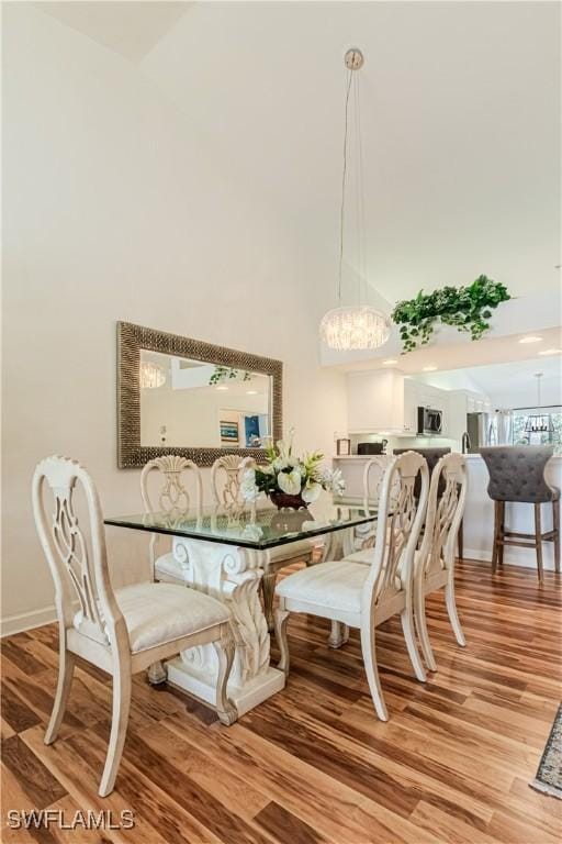 dining space with a high ceiling, baseboards, and wood finished floors