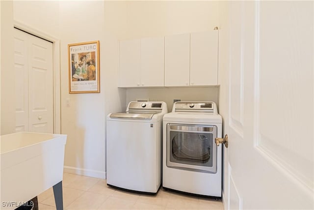 laundry area featuring washer and dryer, cabinet space, light tile patterned floors, and a sink