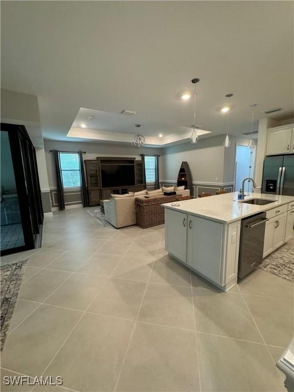 kitchen with sink, white cabinetry, decorative light fixtures, black dishwasher, and an island with sink