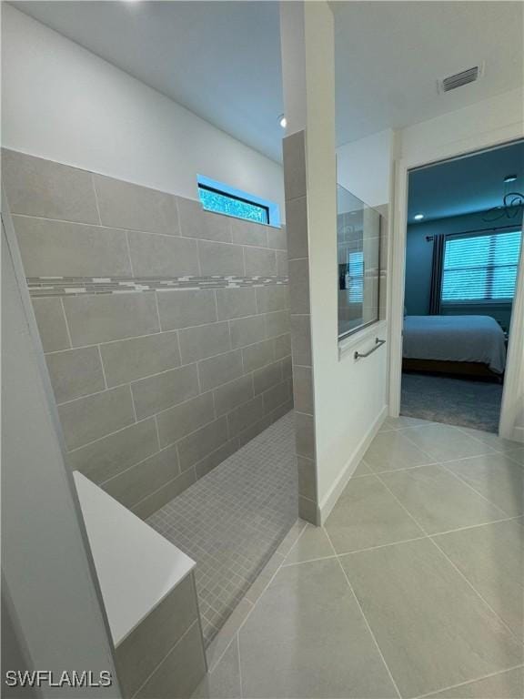 bathroom featuring a tile shower, a wealth of natural light, and tile patterned floors